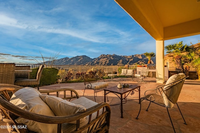 view of patio with an outdoor living space, a mountain view, and fence