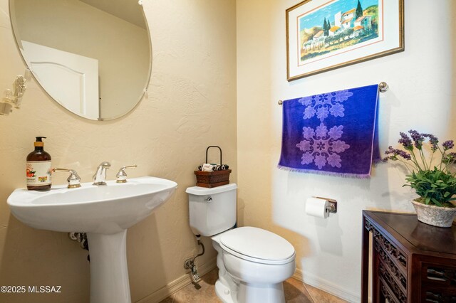 half bathroom with tile patterned floors, baseboards, and toilet
