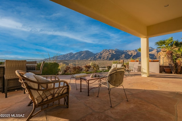 view of patio featuring outdoor dining space, a mountain view, and fence