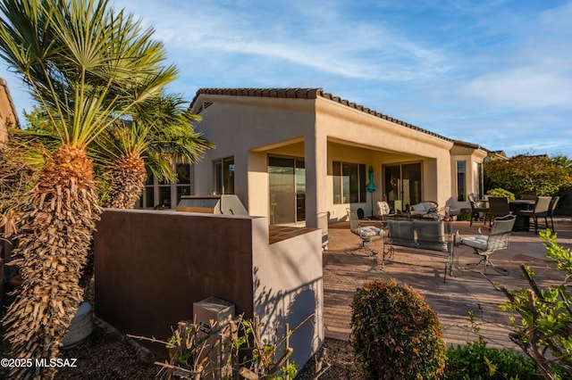 rear view of house with a patio area, stucco siding, and a tile roof