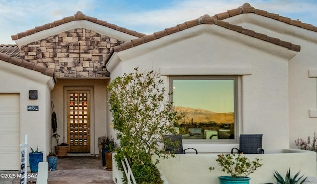 property entrance with a tiled roof and stucco siding