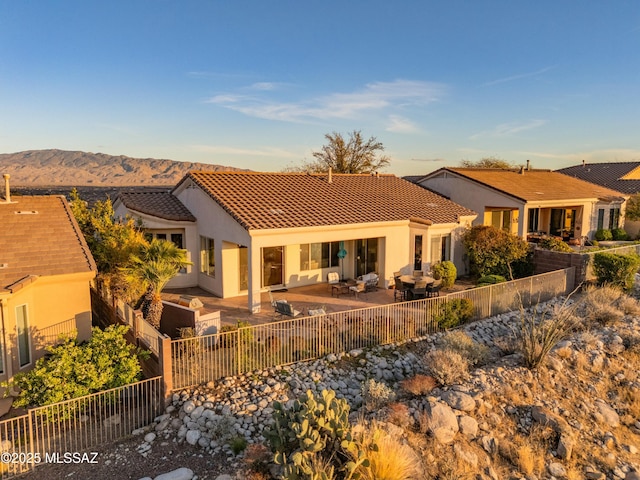 back of house with a patio area, stucco siding, a tile roof, and a fenced backyard