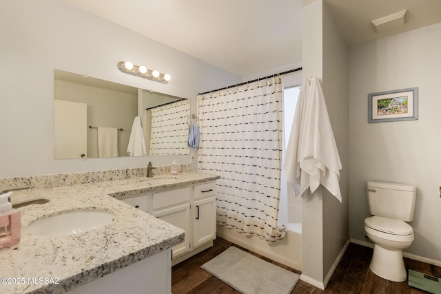 full bath featuring double vanity, a sink, toilet, and wood finished floors