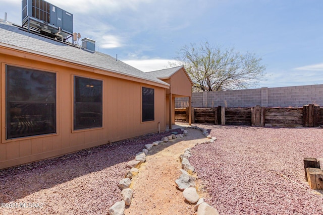 exterior space featuring a chimney, fence, and central AC