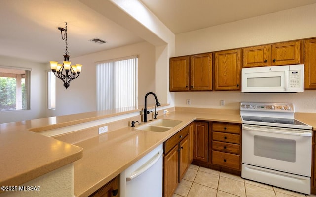 kitchen featuring visible vents, pendant lighting, brown cabinetry, white appliances, and a sink