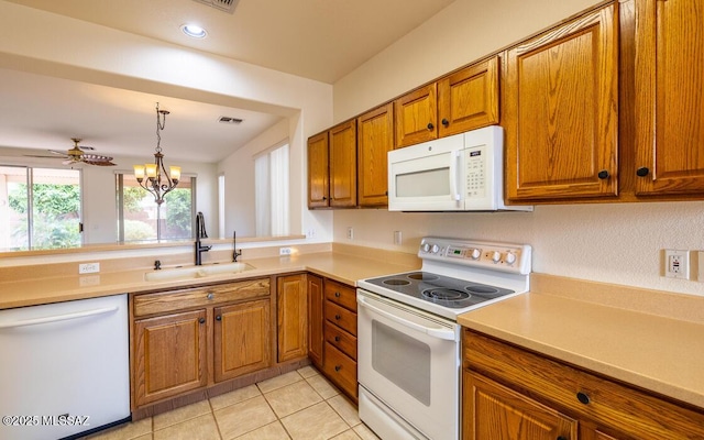 kitchen featuring white appliances, brown cabinetry, visible vents, and a sink