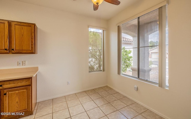 unfurnished dining area featuring light tile patterned floors, baseboards, and a ceiling fan