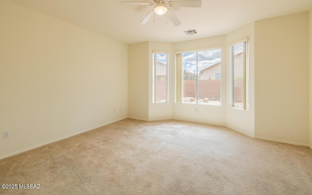 unfurnished room featuring visible vents, light carpet, baseboards, and ceiling fan