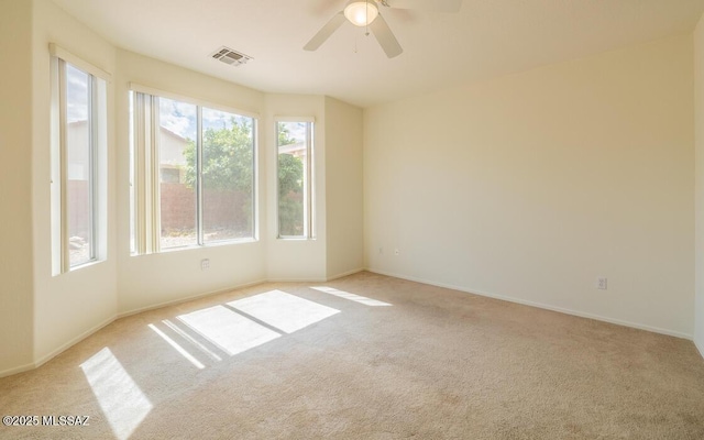 empty room featuring carpet flooring, a ceiling fan, visible vents, and baseboards