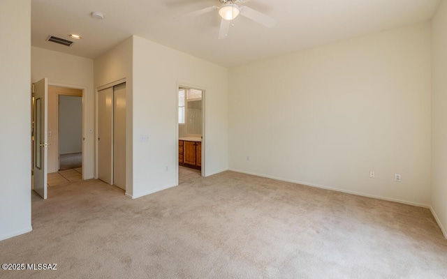 unfurnished bedroom with visible vents, light colored carpet, a closet, and ensuite bathroom