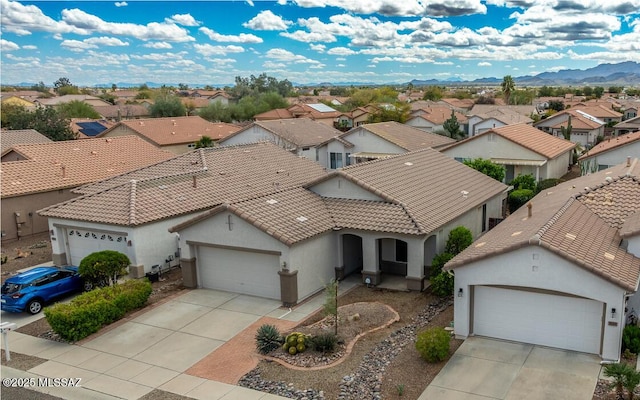 view of front of house featuring stucco siding, driveway, a residential view, a garage, and a tiled roof