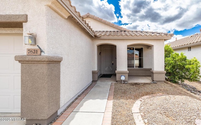 property entrance with stucco siding and a garage