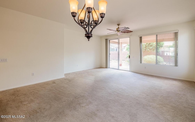 carpeted spare room featuring ceiling fan with notable chandelier