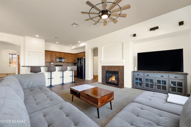 living area with visible vents, dark tile patterned floors, recessed lighting, arched walkways, and ceiling fan