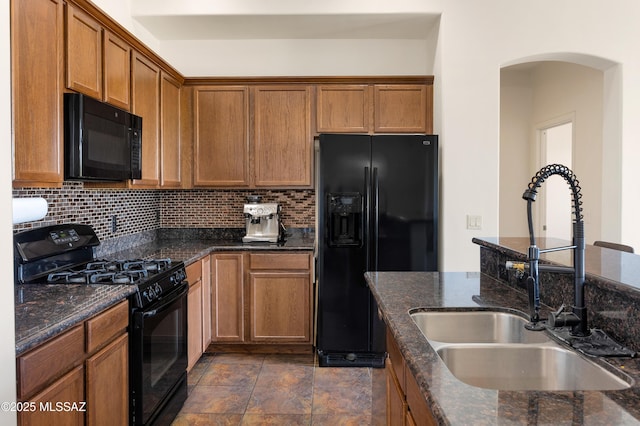 kitchen with a sink, decorative backsplash, brown cabinets, and black appliances