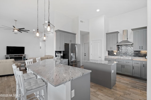 3337 E Wet Sand Pl, Vail, AZ 85641 - kitchen featuring stainless steel fridge, wall chimney exhaust hood, gray cabinets, a ceiling fan, and a towering ceiling