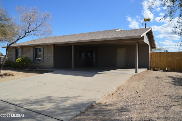 single story home featuring fence, a shingled roof, a carport, concrete driveway, and brick siding