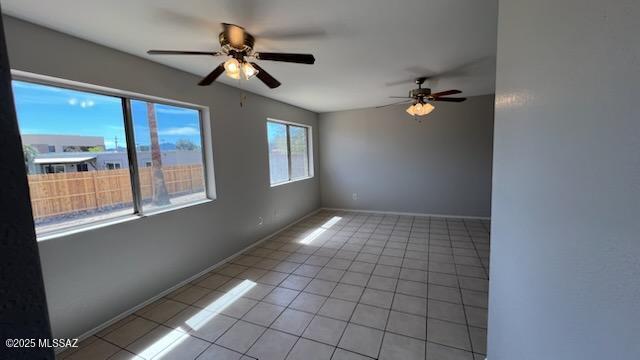 empty room with light tile patterned floors, baseboards, and ceiling fan