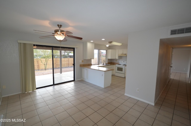 kitchen with a peninsula, white range with electric cooktop, visible vents, white cabinets, and ceiling fan