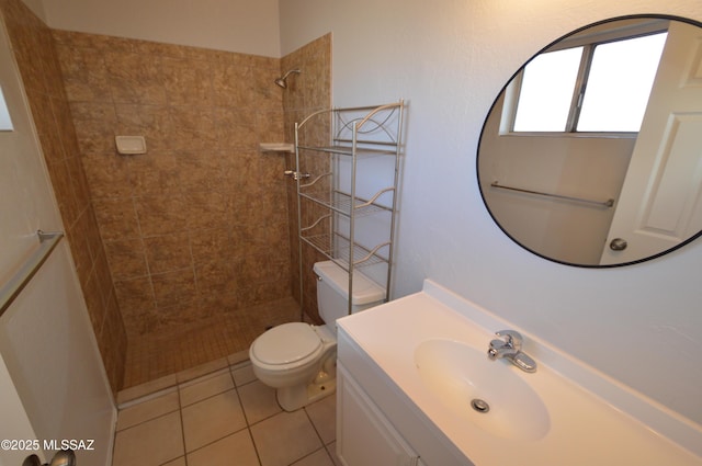 bathroom featuring tile patterned flooring, toilet, vanity, and a tile shower