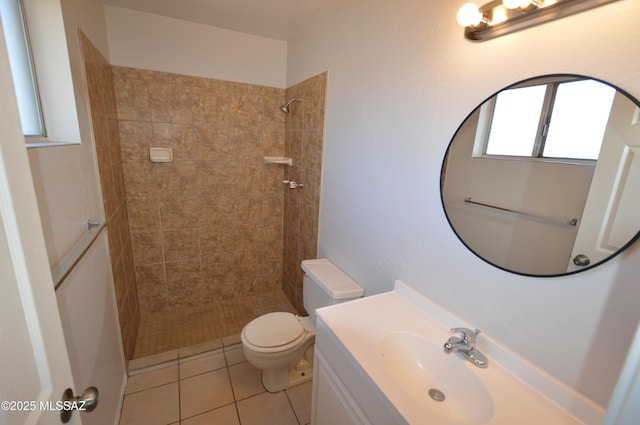 bathroom featuring tile patterned floors, toilet, tiled shower, and vanity