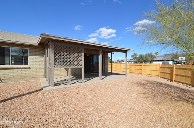 exterior space featuring brick siding, fence, and a patio area