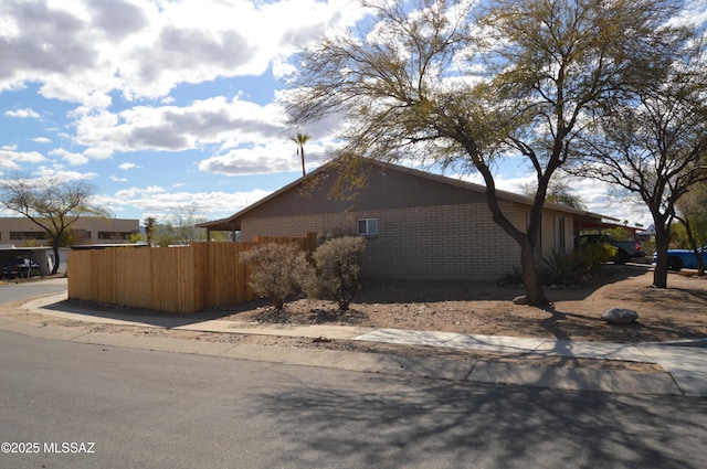 view of side of property with brick siding and fence