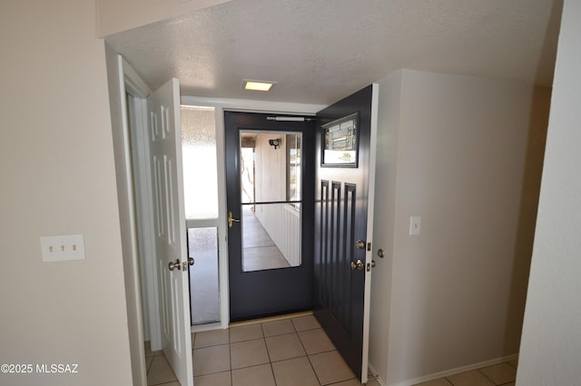 interior space featuring light tile patterned floors, baseboards, and a textured ceiling