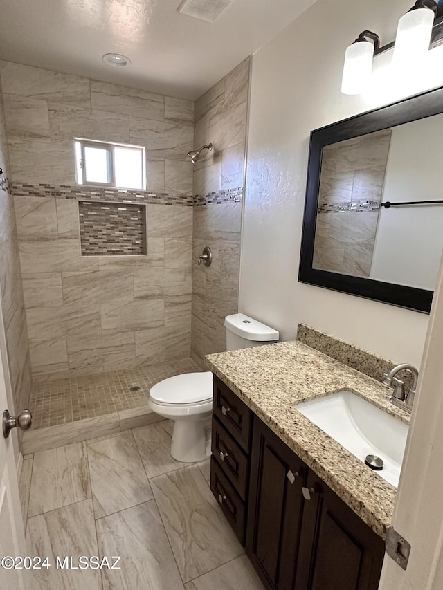 full bath with vanity, toilet, and tiled shower