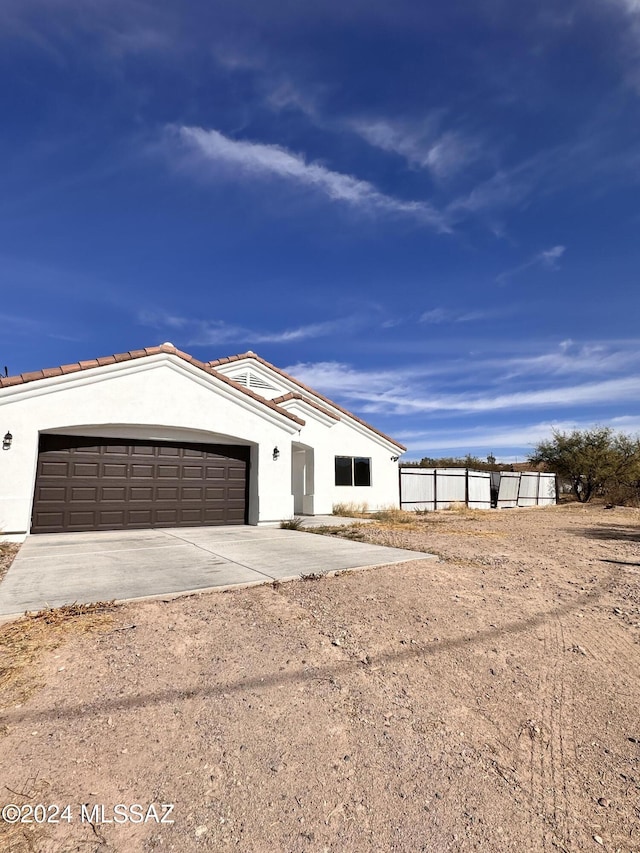 view of front of house featuring an attached garage, fence, driveway, and stucco siding