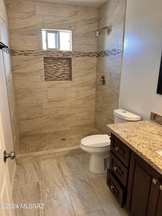 full bath with vanity, toilet, and tiled shower