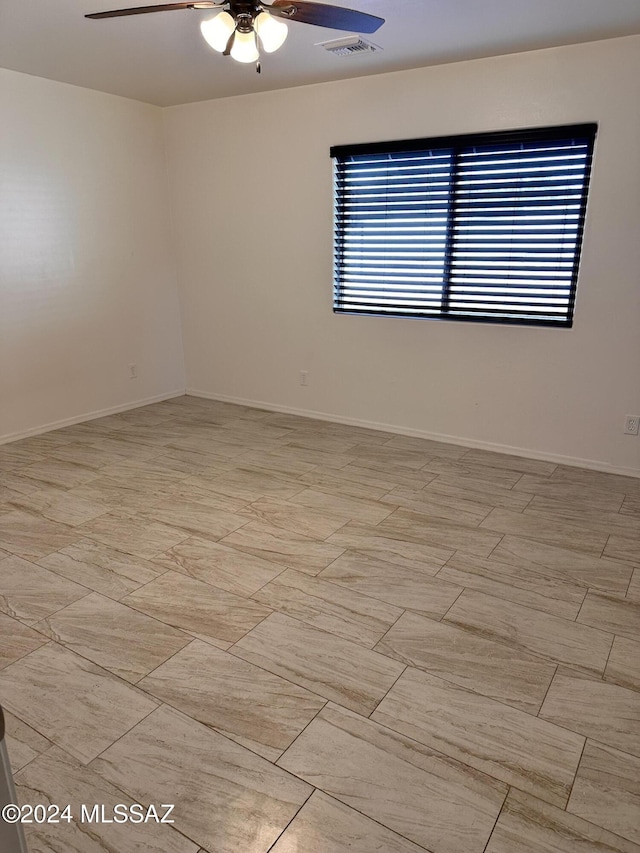 unfurnished room with a ceiling fan, visible vents, and baseboards