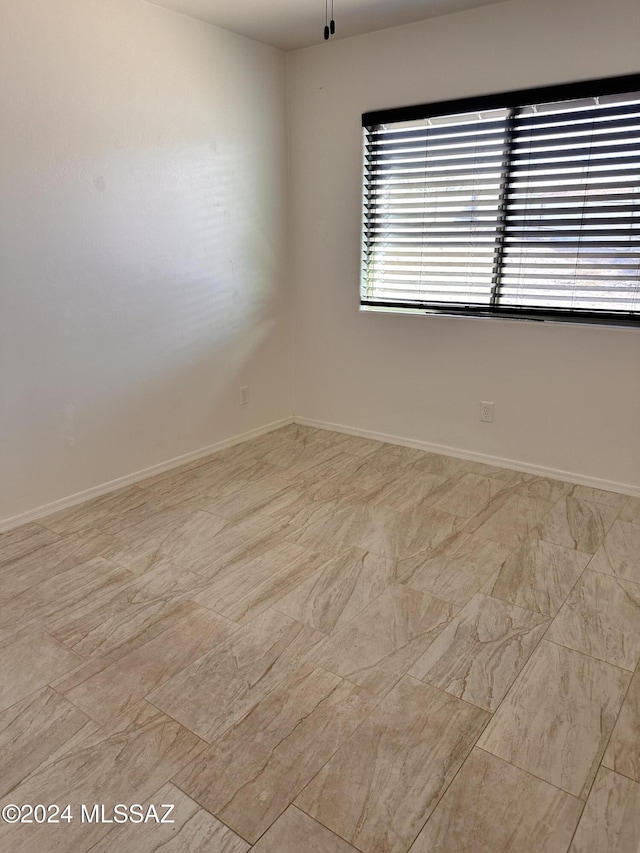 unfurnished room with baseboards