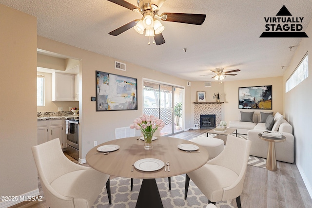 dining room featuring light wood finished floors, visible vents, and a textured ceiling