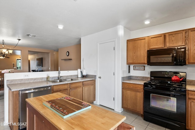 kitchen with brown cabinets, black appliances, a sink, a peninsula, and light tile patterned floors