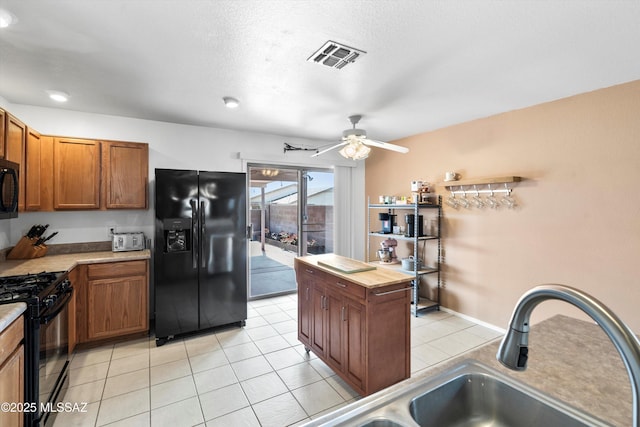 kitchen featuring visible vents, brown cabinets, black appliances, and light tile patterned flooring