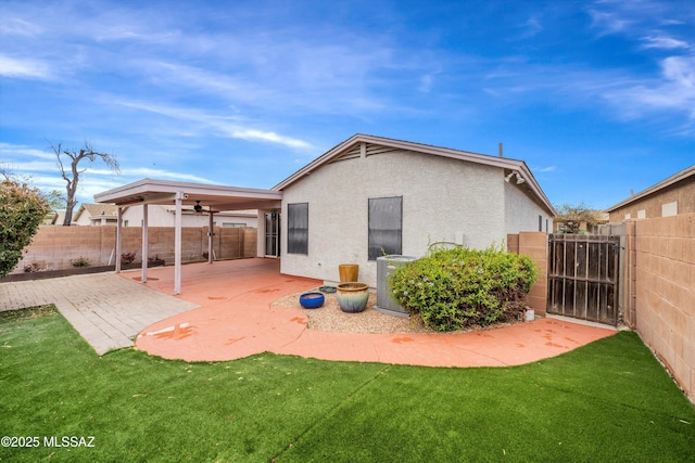 rear view of house featuring a patio, a gate, a fenced backyard, stucco siding, and a lawn