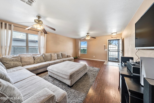 living room featuring visible vents, a ceiling fan, baseboards, and wood-type flooring