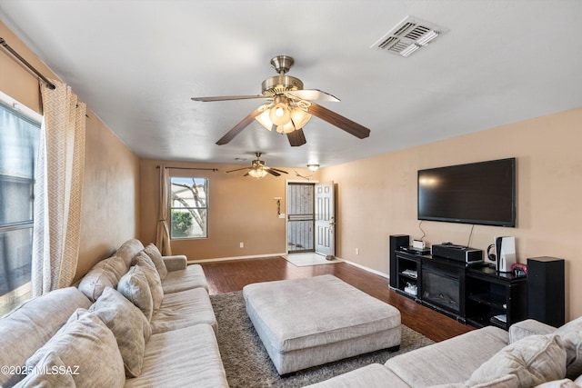 living area featuring a ceiling fan, wood finished floors, visible vents, and baseboards