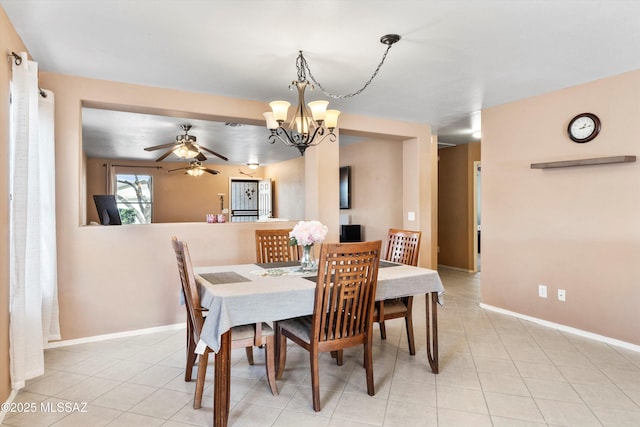 dining area featuring light tile patterned floors, baseboards, and ceiling fan with notable chandelier