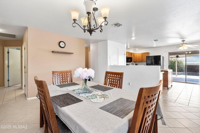 dining space featuring light tile patterned floors, visible vents, and ceiling fan with notable chandelier