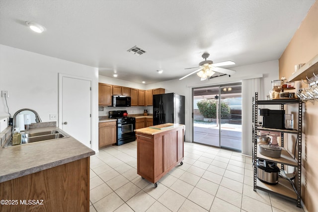 kitchen featuring visible vents, black appliances, a sink, butcher block counters, and light tile patterned floors