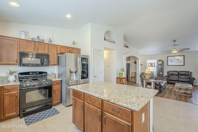 kitchen with arched walkways, light tile patterned floors, black appliances, and ceiling fan