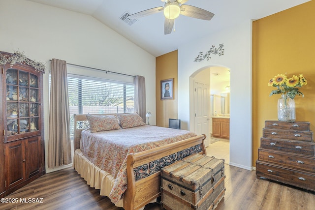 bedroom featuring ensuite bath, wood finished floors, arched walkways, and visible vents