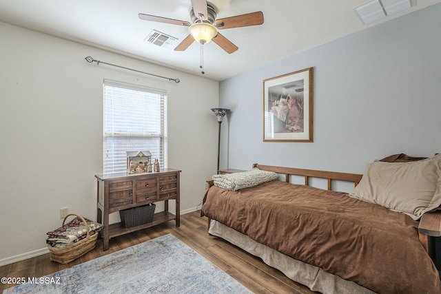 bedroom with wood finished floors, visible vents, and baseboards