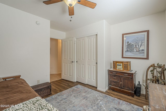 bedroom featuring baseboards, wood finished floors, a closet, and ceiling fan