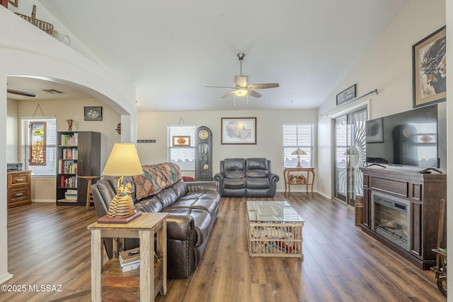 living room featuring vaulted ceiling, a ceiling fan, arched walkways, and a healthy amount of sunlight