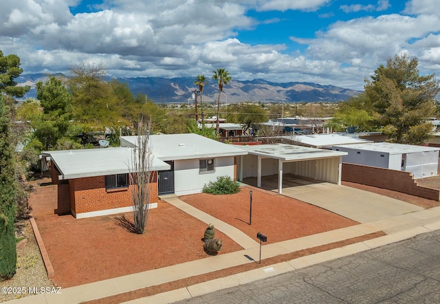 single story home with a mountain view, an attached carport, concrete driveway, and brick siding