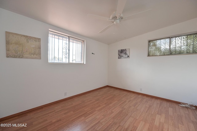 spare room featuring baseboards, ceiling fan, and light wood finished floors