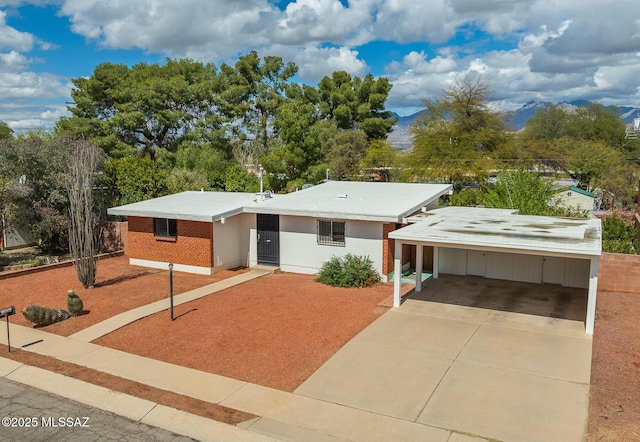 view of front facade featuring brick siding, a mountain view, driveway, and a carport